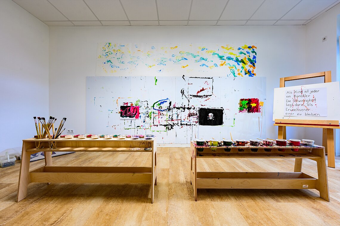 Eine Kunstwerkstatt mit Staffeleien und Gemälden an der Wand, die sich einem pädagogischen Konzept für frühkindliche Bildung in AWO-Kitas wid