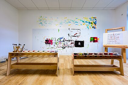 Eine Kunstwerkstatt mit Staffeleien und Gemälden an der Wand, die sich einem pädagogischen Konzept für frühkindliche Bildung in AWO-Kitas wid