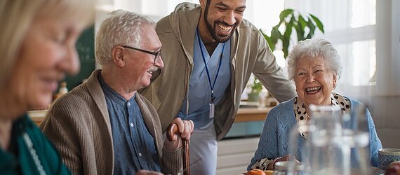 Eine Betreuungsgruppe von Senior:innen frühstückt in einer Tagespflegeeinrichtung der AWO Mönchengladbach und erhält Unterstützung.