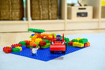Ein Satz Legosteine auf dem Boden in einem Raum, der frühkindliche Bildung fördert und einem offenen pädagogischen Konzept in AWO-Kitas folgt.